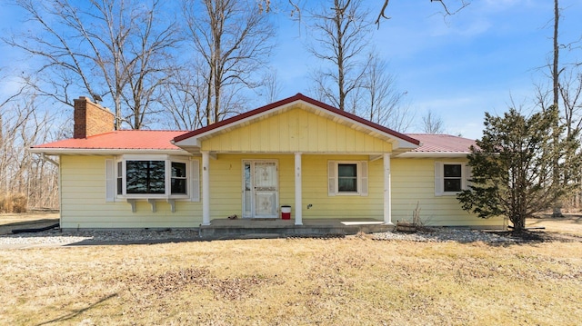 view of front of property with a chimney, covered porch, and metal roof