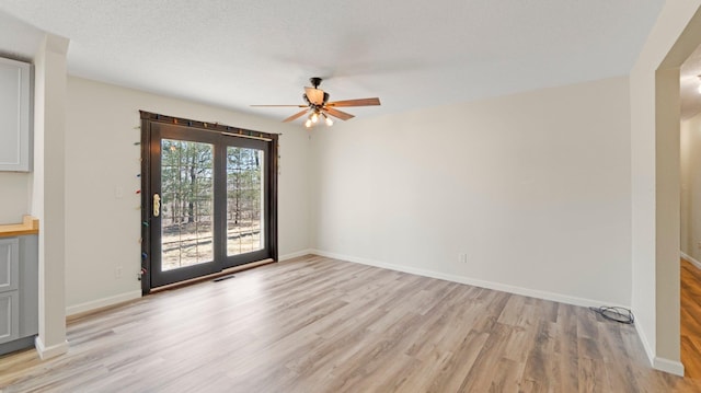 empty room with a ceiling fan, visible vents, baseboards, and light wood-type flooring