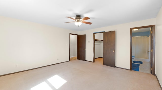 unfurnished bedroom featuring a spacious closet, light colored carpet, a closet, and baseboards