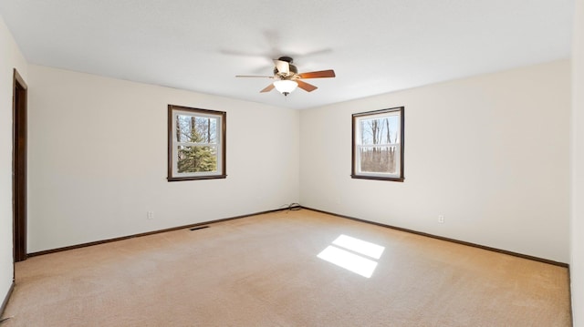 unfurnished room featuring light carpet, visible vents, ceiling fan, and baseboards