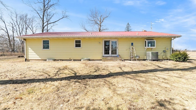 back of house featuring metal roof, central AC unit, and entry steps