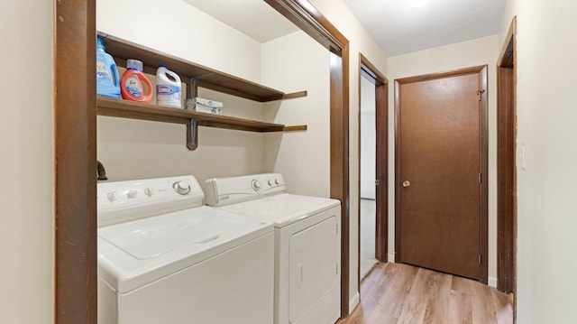 laundry area with laundry area, washing machine and dryer, and light wood-style flooring