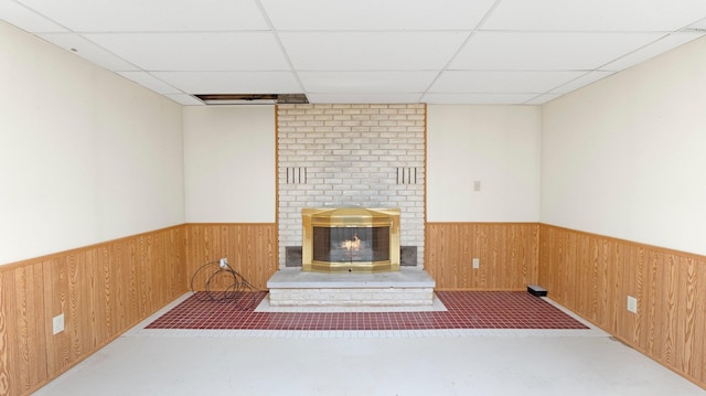 interior space featuring wooden walls, wainscoting, a fireplace, and a paneled ceiling