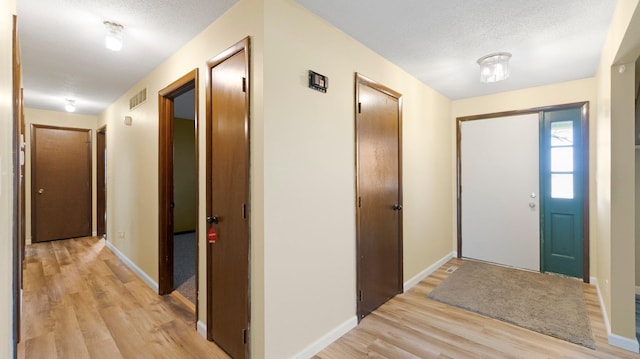 entrance foyer with baseboards, visible vents, a textured ceiling, and light wood-style floors