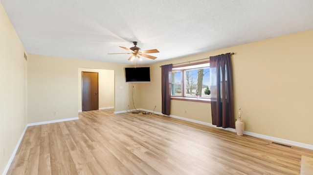 empty room featuring baseboards, visible vents, a textured ceiling, and light wood-style floors