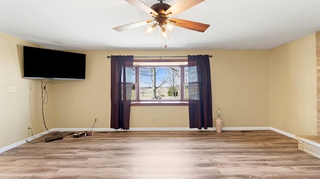 spare room featuring ceiling fan, a textured ceiling, baseboards, and wood finished floors