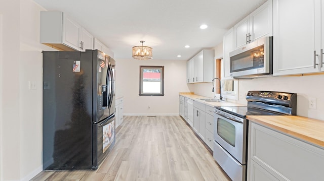 kitchen featuring a sink, light wood-style flooring, appliances with stainless steel finishes, and white cabinets