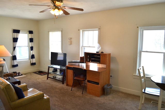 carpeted office space featuring a ceiling fan and baseboards