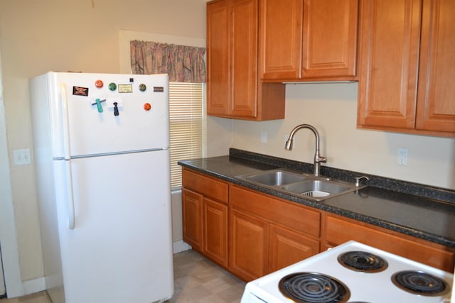 kitchen with brown cabinets, a sink, dark countertops, white appliances, and light floors