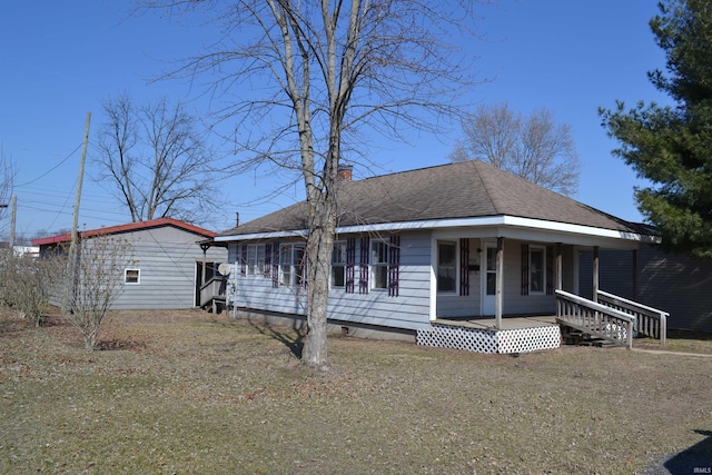 view of front of home featuring a porch, roof with shingles, and a chimney