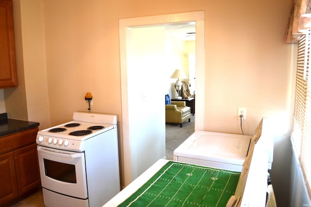 kitchen with brown cabinets, carpet, and white electric range oven