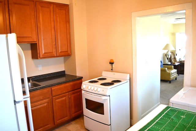 kitchen with a sink, white appliances, brown cabinets, and light carpet