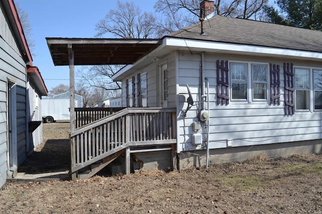 view of side of home featuring a chimney and roof with shingles