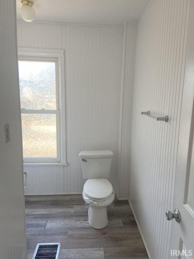 bathroom with toilet, wood finished floors, visible vents, and a wealth of natural light