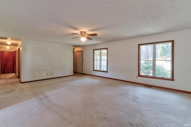 spare room with baseboards, light colored carpet, visible vents, and a textured ceiling