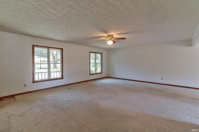 carpeted spare room with ceiling fan, baseboards, and a textured ceiling