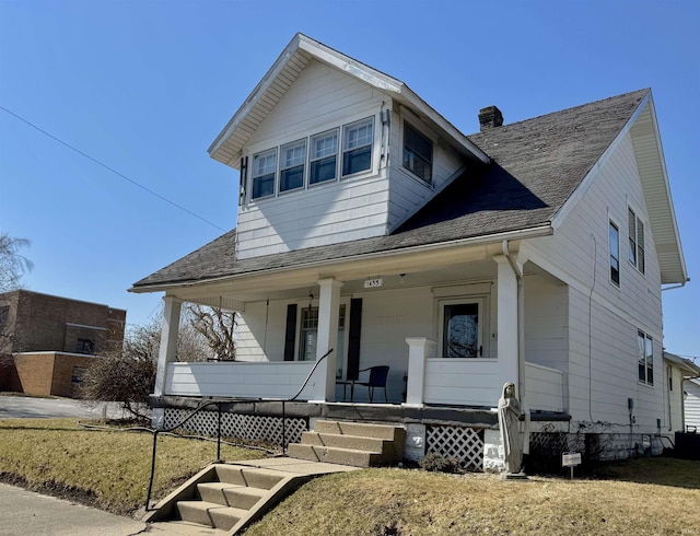 view of front of house with a shingled roof, a porch, and a chimney