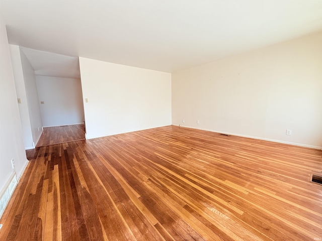 empty room with hardwood / wood-style floors and visible vents