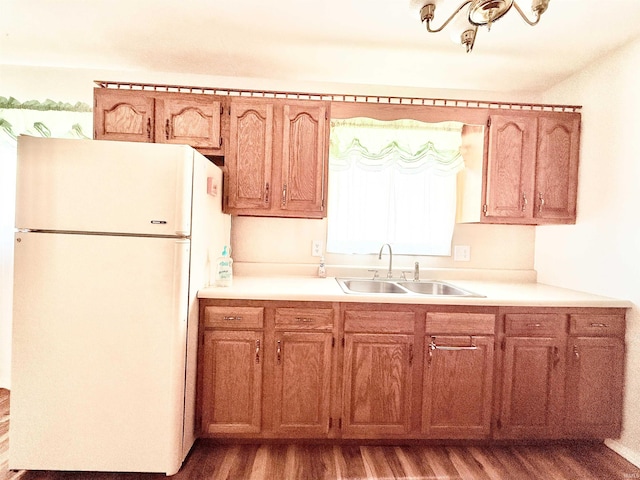 kitchen featuring wood finished floors, freestanding refrigerator, a sink, light countertops, and brown cabinets