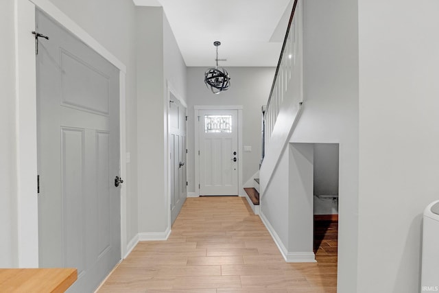 foyer with light wood finished floors, stairway, an inviting chandelier, and baseboards