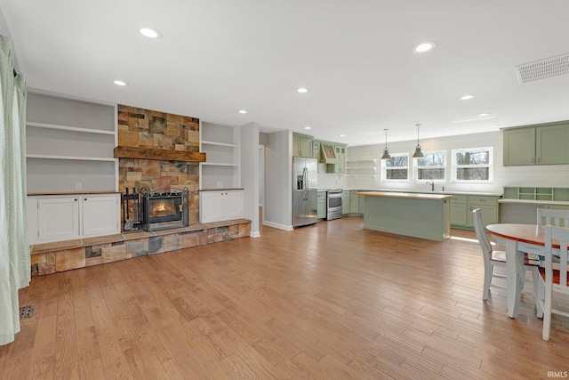 living area with light wood finished floors, visible vents, recessed lighting, and a fireplace