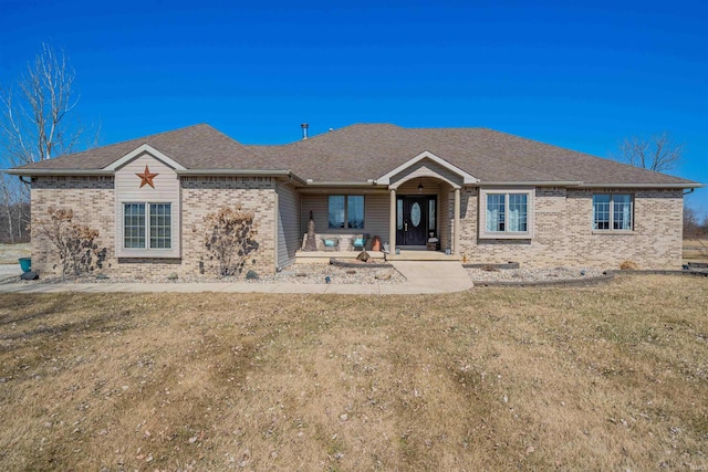 single story home with brick siding, a front lawn, and a shingled roof