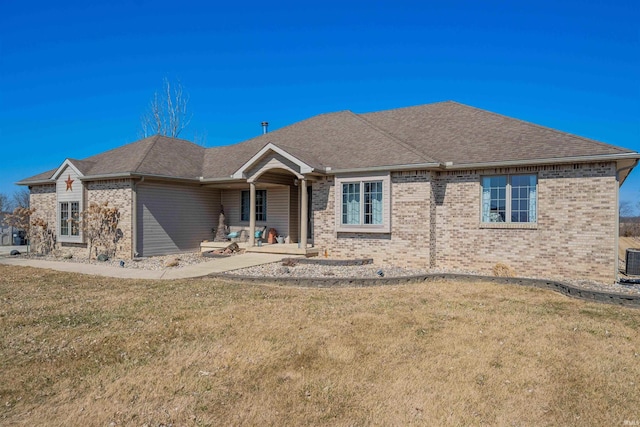 ranch-style home with a front yard, central air condition unit, brick siding, and a shingled roof