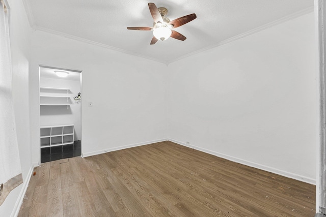 spare room featuring a ceiling fan, wood finished floors, baseboards, and ornamental molding