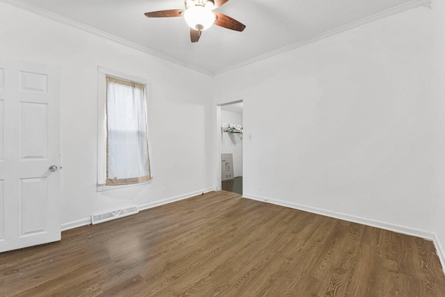 spare room featuring visible vents, crown molding, baseboards, and wood finished floors