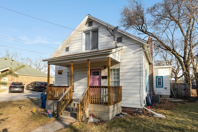 view of front facade featuring central air condition unit, a porch, and a chimney