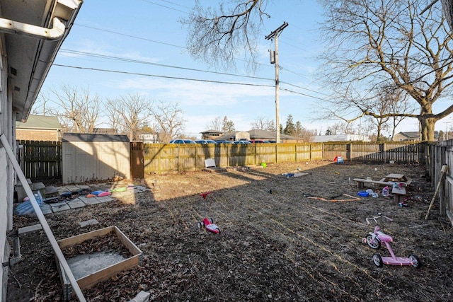 view of yard featuring a garden, a fenced backyard, an outdoor structure, and a shed