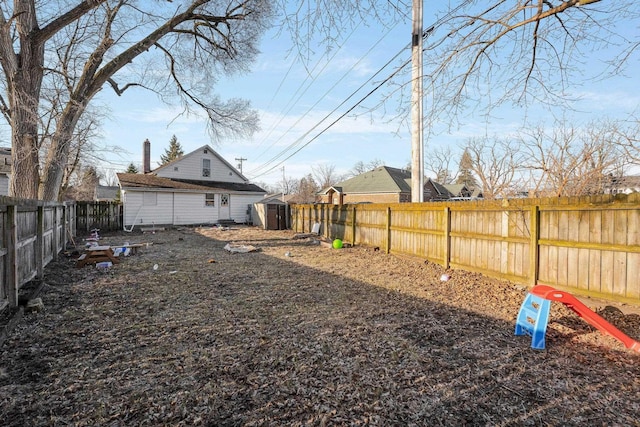 view of yard with a storage shed, an outbuilding, and a fenced backyard