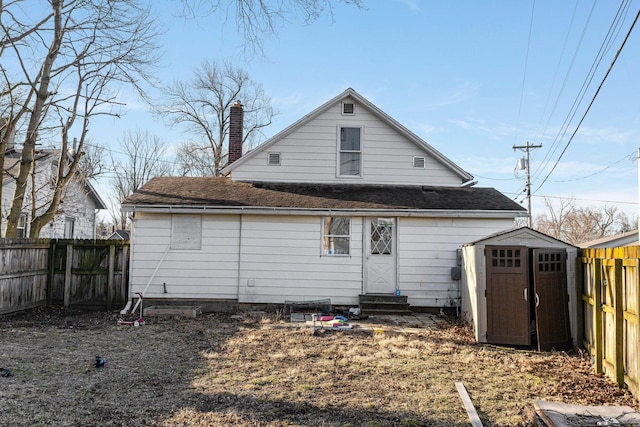 rear view of property featuring entry steps, an outdoor structure, a fenced backyard, and a chimney