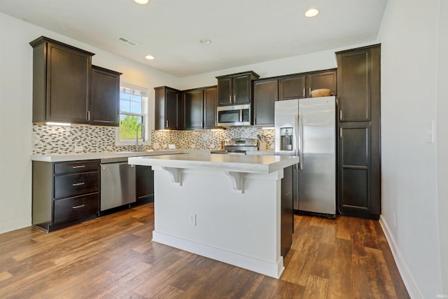 kitchen with visible vents, stainless steel appliances, a breakfast bar area, light countertops, and decorative backsplash