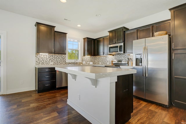 kitchen with stainless steel appliances, dark wood-type flooring, tasteful backsplash, and dark brown cabinetry