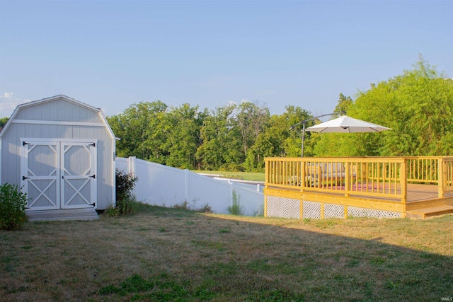 view of yard with an outbuilding, a shed, a wooden deck, and a fenced backyard