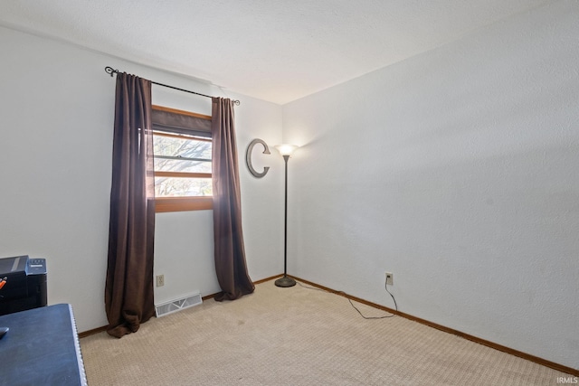 spare room with baseboards, visible vents, and light carpet