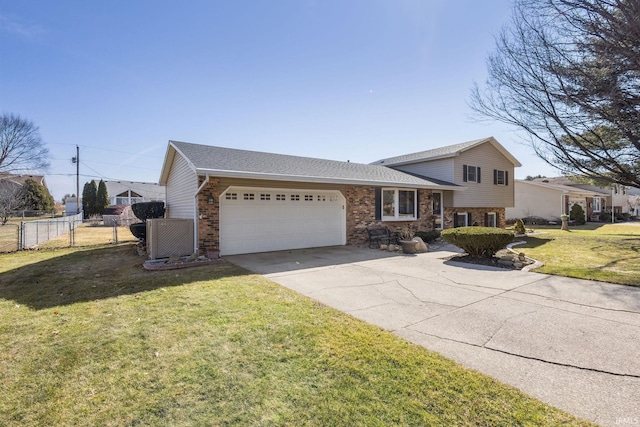 tri-level home featuring a front yard, fence, brick siding, and a garage