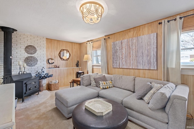 living room featuring wood walls, a textured ceiling, a wood stove, and carpet