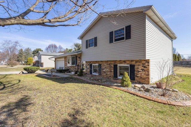 exterior space featuring a yard, brick siding, an attached garage, and fence