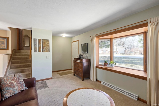 living room with baseboards, light colored carpet, stairs, baseboard heating, and a textured ceiling