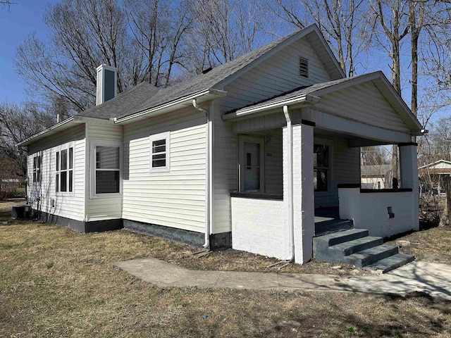 view of property exterior with a shingled roof, a porch, cooling unit, and a chimney