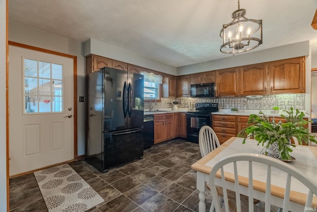 kitchen featuring brown cabinetry, a sink, decorative backsplash, black appliances, and light countertops