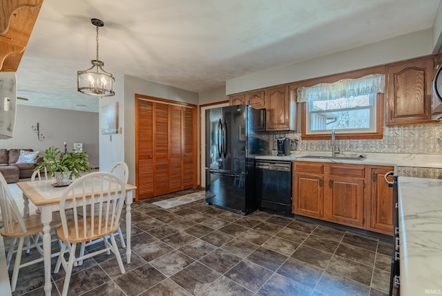 kitchen with a sink, black appliances, light countertops, pendant lighting, and tasteful backsplash