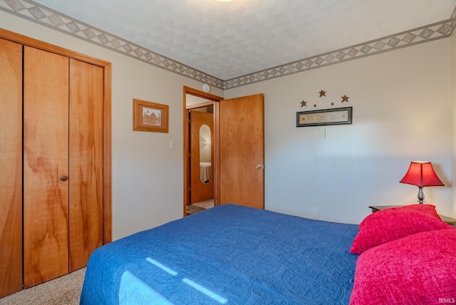 bedroom featuring a closet, carpet flooring, and arched walkways