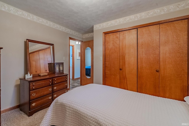 bedroom with a closet, a textured ceiling, light carpet, and baseboards