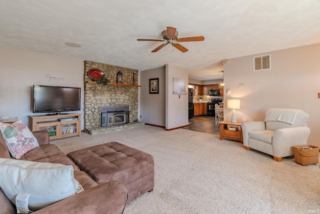 living area with visible vents, baseboards, light carpet, a textured ceiling, and a ceiling fan