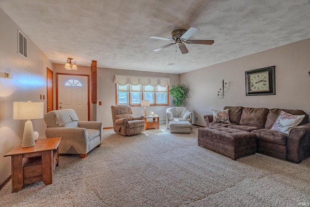 living room featuring visible vents, ceiling fan, baseboards, carpet floors, and a textured ceiling