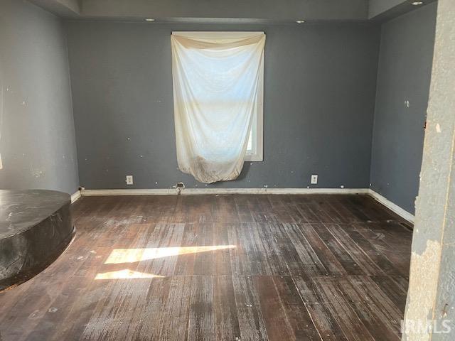 unfurnished room with baseboards and hardwood / wood-style flooring