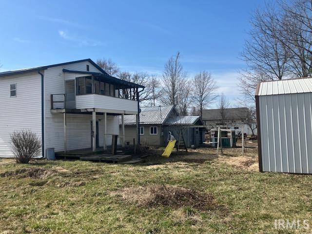 back of house featuring a storage shed, an outbuilding, a playground, and a yard